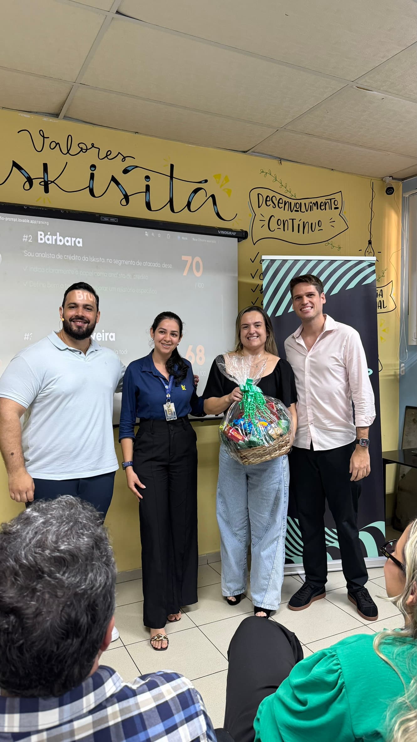 Entrega da recompensa a uma participante ao fim do desafio, com a pontuação projetada atrás do grupo