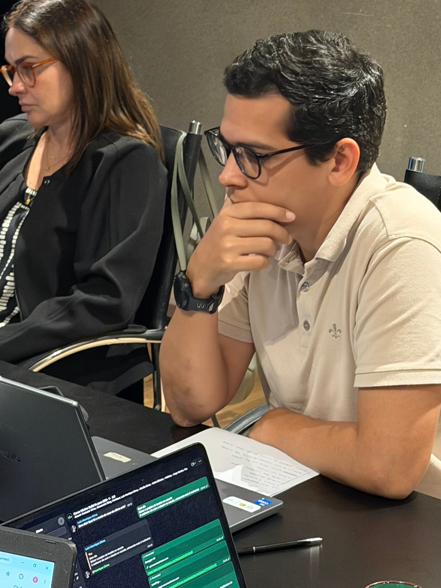 Dois participantes lado a lado acompanham a aula, com notebooks e um tablet abertos sobre a mesa