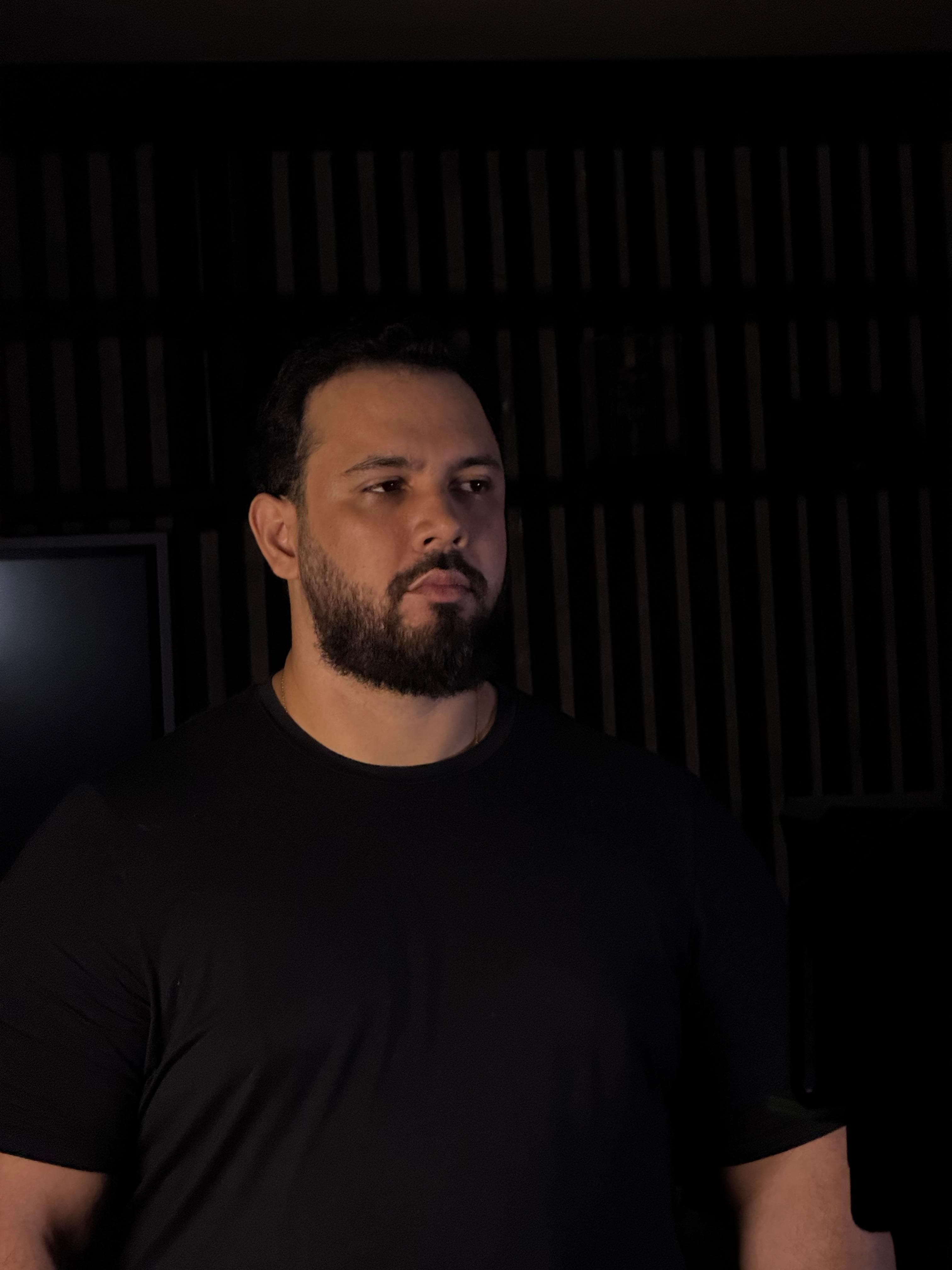Mentor diante de um painel ripado escuro, olhando para o lado com expressão serena